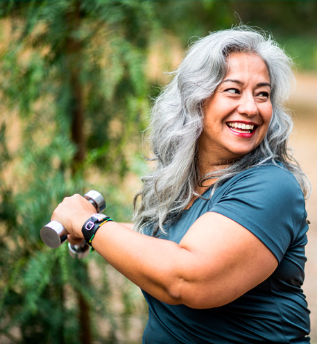 Mujer sonriendo mientras hace ejercicio al aire libre.